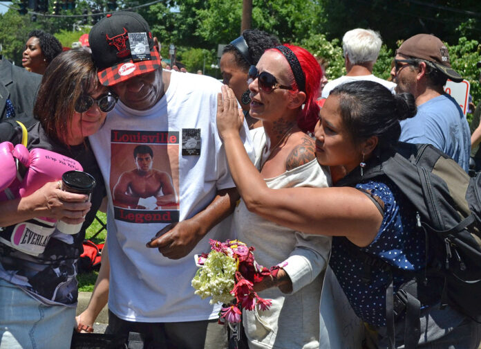 Gerald Wayne Jacobs is consoled by strangers as he cries at the gates of Cave Hill cemetery Friday in Louisville, Kentucky. Photo: Dylan Lovan / Associated Press